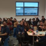 International Student Society members gathered for a social event in a classroom, engaging and interacting with each other.